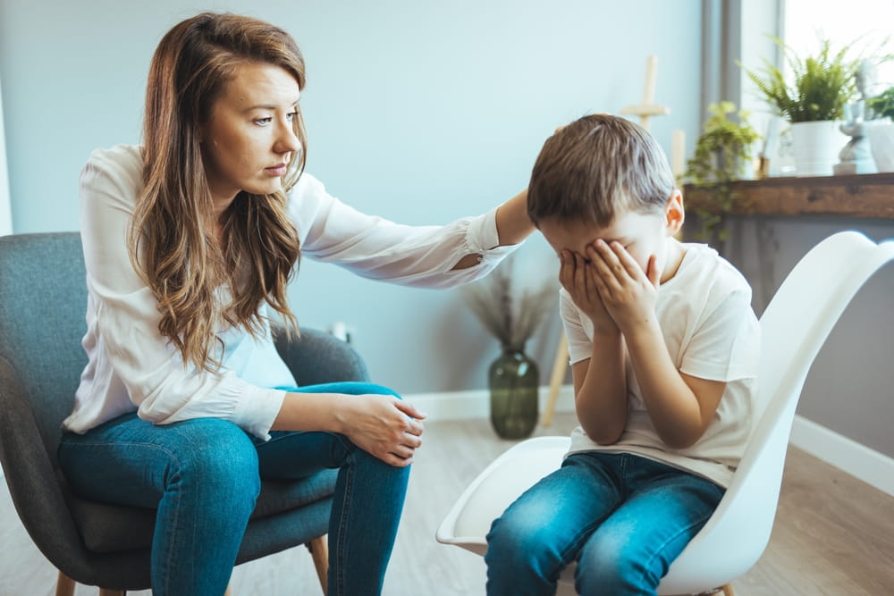Parenthood and child development, young worried mother comforting little son crying at home