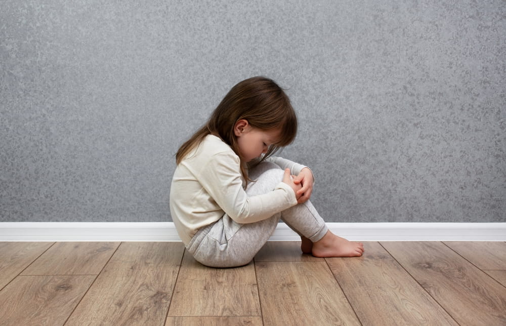Sad and lonely child sitting alone near the wall. Domestic violence against children.